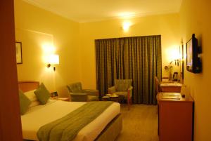 a hotel room with a bed and a chair and a window at Beverly Hotel in Chennai