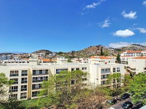 ein großes weißes Gebäude mit einer Stadt im Hintergrund in der Unterkunft Gardenia Apartment by LovelyStay in Funchal
