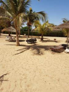 a sandy beach with palm trees and benches and umbrellas at appartementsurlaplage in Saly Portudal
