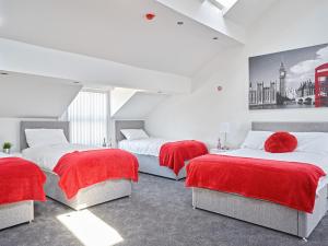 a bedroom with three beds with red blankets and a painting on the wall at 88 Anfield Road in Liverpool