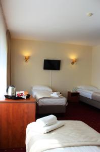 a hotel room with three beds and a flat screen tv at Hotel Biały in Wałbrzych
