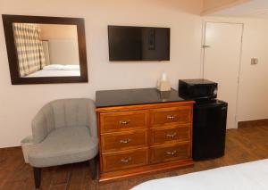 1 dormitorio con silla y vestidor con TV en Budgetel Inn & Suites, en Yuma