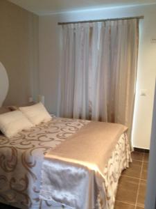 a bedroom with a bed and a window with curtains at Apartamentos Torremenguada in Torremenga