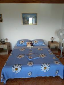 een bed met een blauw dekbed met bloemen erop bij Robinson Crusoe in Drage