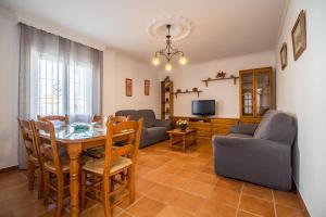 een woonkamer met een tafel en stoelen en een televisie bij Chalet adosado Atalaya F in Conil de la Frontera