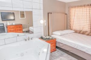 a bedroom with a bed and a tub and a sink at Budgetel Inn & Suites in Yuma