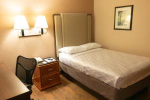 a hotel room with a bed and a table with a phone at Budgetel Inn & Suites in Yuma