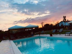 a large swimming pool with chairs and a gazebo at Agriturismo Quercetelli in Castiglione del Lago