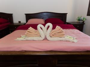 Dois cisnes para parecerem corações sentados numa cama. em Гурме хаус em Gabrovo