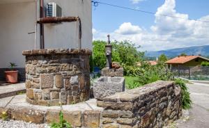 a stone wall next to a building with a statue at Hiška pod Krasom in Renče