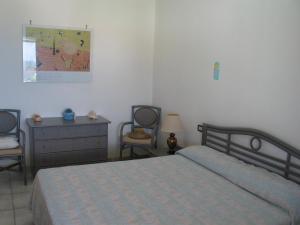 sypialnia z łóżkiem, 2 krzesłami i komodą w obiekcie Villa Marisa Paestum w mieście Paestum