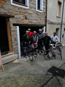 un gruppo di persone in piedi fuori da un edificio con le loro biciclette di Antico Restauro a Fonni