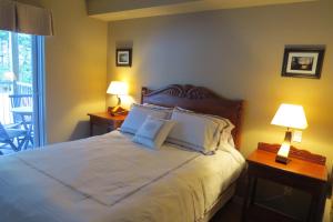 1 dormitorio con 1 cama con 2 lámparas y balcón en Appart-hôtel Villégiature Saint-Sauveur, en Piedmont