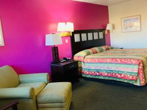 a hotel room with two beds and a chair at Luxury Inn in Albuquerque
