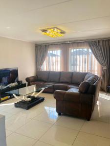 a living room with a brown couch and a glass table at Cluster 59 Issa in Midrand