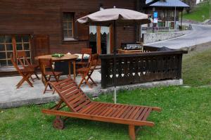 萊迪亞布勒雷的住宿－Chalet Floriana，院子里的木椅和带雨伞的桌子