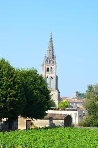 a church steeple in the distance with a tree in the foreground at Coup 2 Foudres in Saint-Jean-de-Blaignac