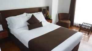 a bedroom with a large bed and a chair at Hotel Casa Galvez in Manizales