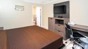 a hotel room with a bed and a desk and a television at Sea Rock Inn - Long Beach in Long Beach