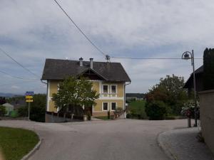 a yellow house with a black roof on a street at Hartl Apartments in Kirchberg ob der Donau