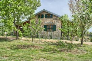 an old stone house with green shutters and trees at STONE HOUSE VLASTA in Drniš