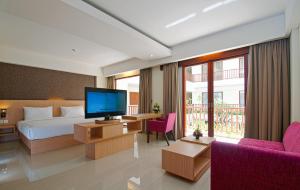 a hotel room with a bed and a television at Sense Sunset Hotel Seminyak in Seminyak