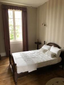 Un dormitorio con una cama con sábanas blancas y una ventana. en Chateau de Grand Bonnefont, en Limoges 30 fotos más