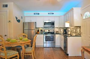 una cocina con armarios blancos y una mesa con sillas. en Crescent Beach 1011 #1, en Sarasota