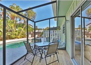 un patio con mesa, sillas y piscina en Crescent Beach 1011 #1, en Sarasota