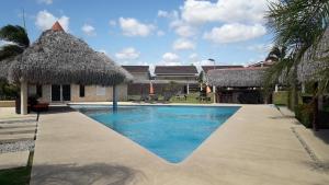 a swimming pool with a thatch roof at Coronado Beach Paradise in El Llano del Medio