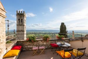een balkon met een tafel en stoelen en een klokkentoren bij Room En Suite la Corte Assisi in Assisi