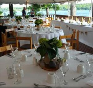 a dining room with white tables with glasses and flowers at Westwind Inn on the Lake in Buckhorn