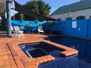 una piscina con mesa y sillas junto a una casa en Blue Pelican Motel, en Tweed Heads