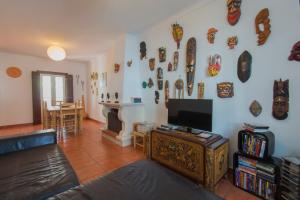 a living room with a couch and a tv on a wall at SUNNY HOUSE by Stay in Alentejo in Vila Nova de Milfontes
