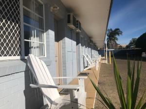 a row of white benches on the side of a building at Blue Pelican Motel in Tweed Heads
