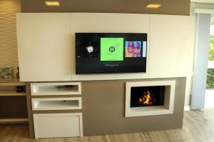 Apto Novo e Moderno no Centro de Gramado في غرامادو: غرفة معيشة مع تلفزيون ومدفأة