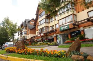 Apto Novo e Moderno no Centro de Gramado في غرامادو: مبنى أمامه زهور