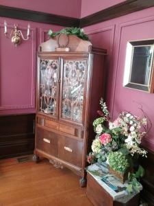 a purple room with a china cabinet and flowers at Hanover House Bed and Breakfast in Niagara Falls