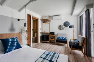 a hotel room with a bed and a tv and chairs at HOMM Boutique Hotel in Chiang Mai