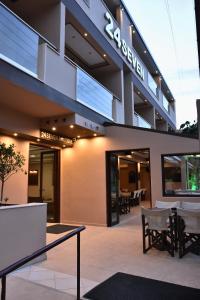 a building with tables and chairs in front of it at 24 Seven Boutique Hotel in Malia