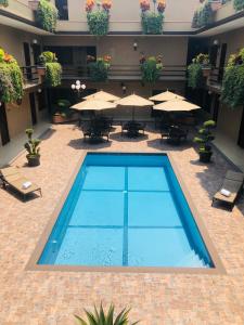 a swimming pool in a courtyard with tables and umbrellas at Hotel Layfer del Centro, Córdoba, Ver in Córdoba