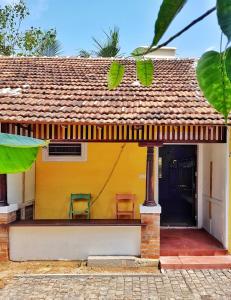ein gelbes Haus mit zwei Stühlen davor in der Unterkunft Design Ashram in Kozhikode