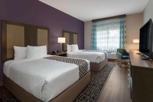 a hotel room with two beds and a television at La Quinta by Wyndham Wichita Airport in Wichita