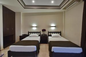 two beds in a hotel room with flowers on the wall at 24 Seven Boutique Hotel in Malia