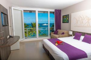 a hotel room with a bed and a view of the ocean at Hotel Beaurivage in Noumea