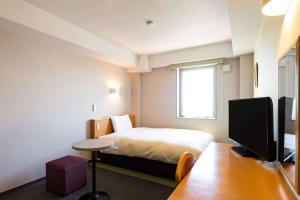 a hotel room with a bed, desk and television at Comfort Inn Kashima in Fukashiba
