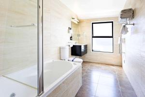 uma casa de banho com uma banheira, um WC e um chuveiro em Alexander Inn em Auckland