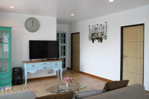 Una sala de estar con televisión y un sofá. en Thacha Pool Villa A, en Hua Hin