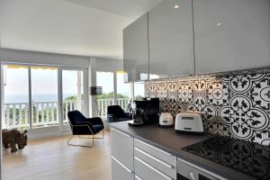a kitchen with a counter and some chairs and windows at Les Terrasses du parc Cordier in Trouville-sur-Mer