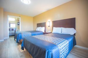 Habitación de hotel con 2 camas con sábanas azules en The Crossroads Hotel and Suites Irving, en Irving